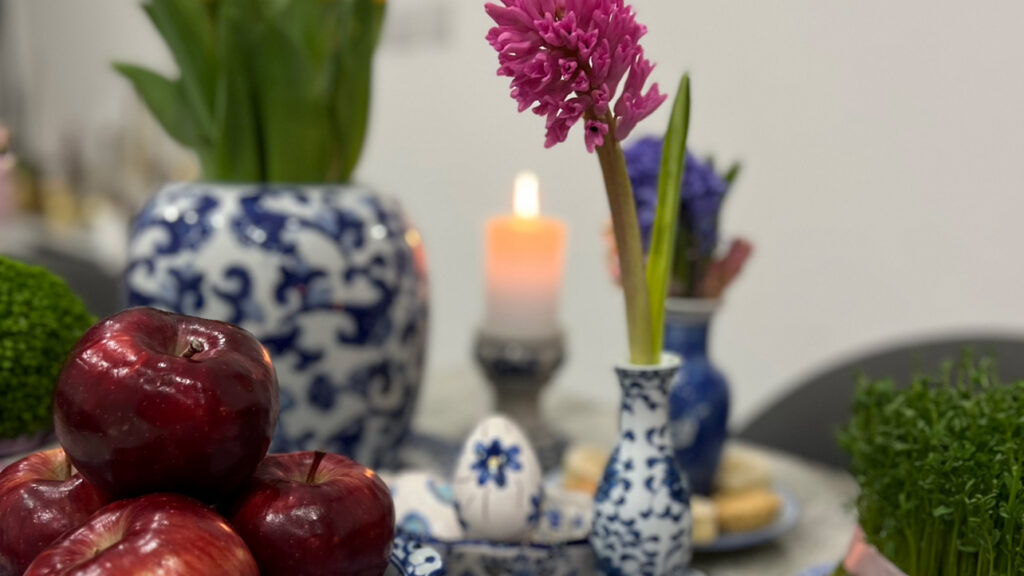 Close-up of a traditional Haft Sin table with apples, hyacinth flowers, candles, and Persian decorations celebrating Nowruz in Toronto