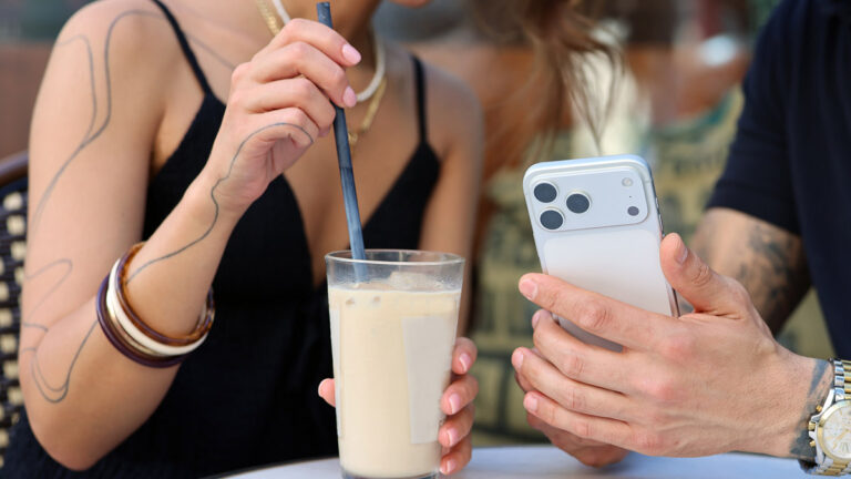 Zwei Personen betrachten gemeinsam ein Smartphone in einem Café