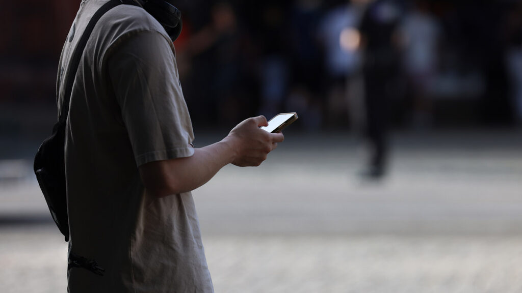 Person nutzt unterwegs ein Smartphone für die Online-Partnersuche