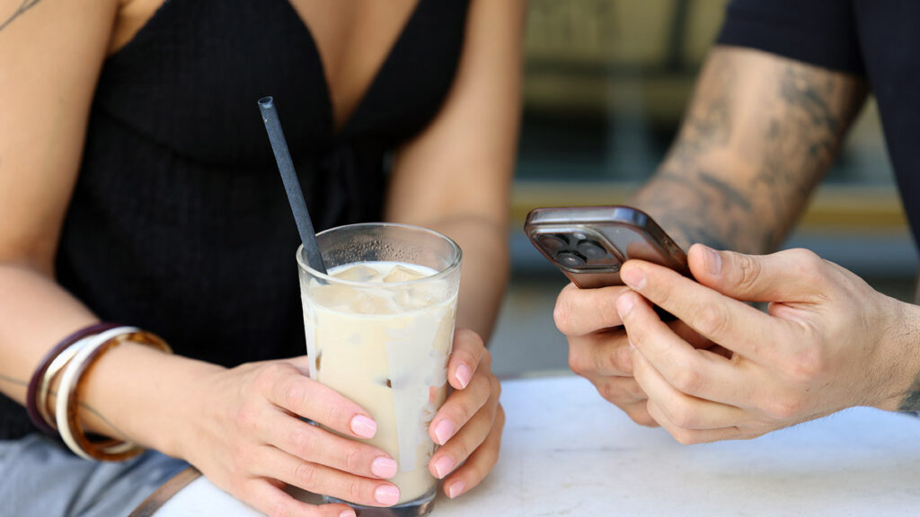 Persian couple using a dating app at a cafe in Germany