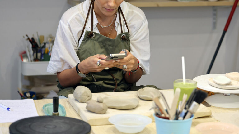 Iranian woman using her phone during a pottery workshop at Dream Poetry Cafe in Düsseldorf, Germany