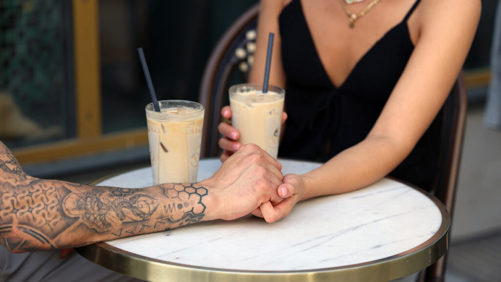 Couple holding hands at a cafe, representing affection, trust, and romance in Persian relationships