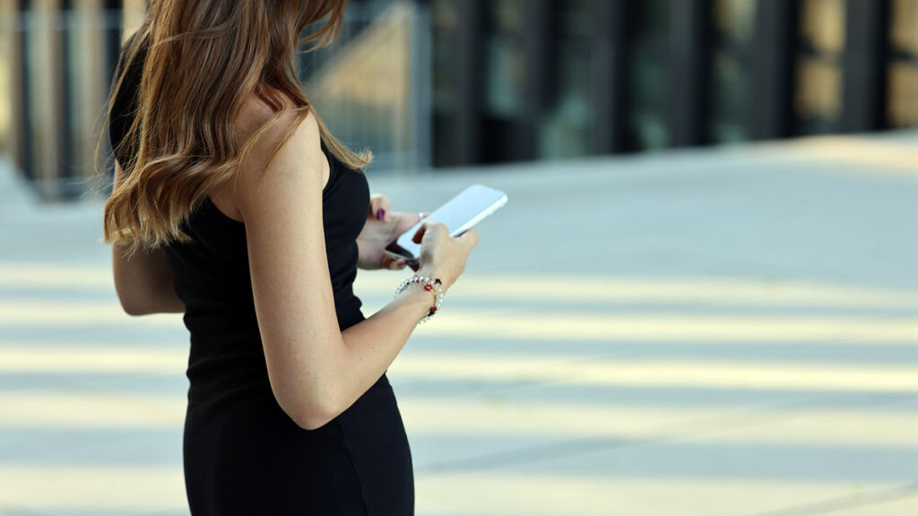 Junge Frau nutzt unterwegs eine Dating-App auf ihrem Smartphone