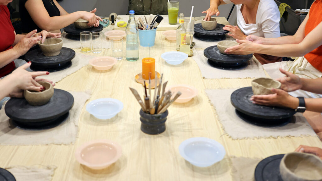 Gruppe formt gemeinsam Keramik an einem Tisch in einem Workshop