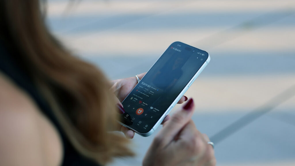 Woman browsing profiles on the KIBAKI dating app for Persian speakers