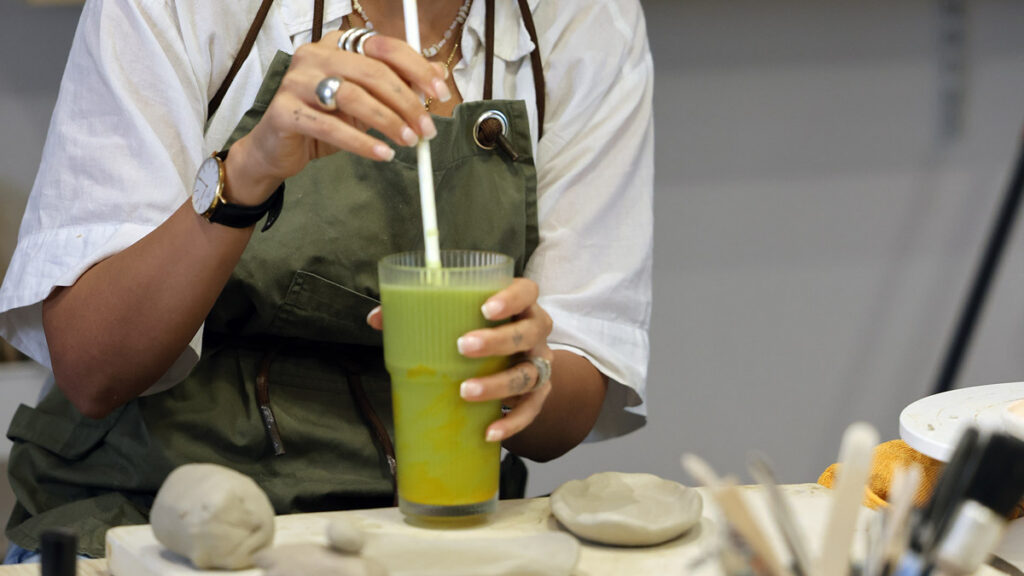 Woman holding a fresh drink during a casual creative workshop
