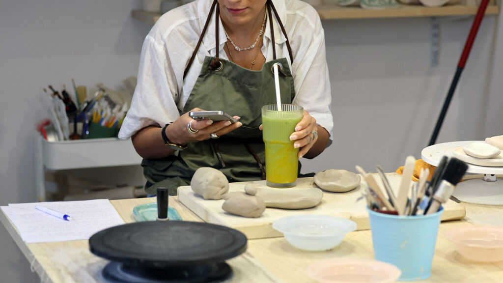 Junge Frau bei einem gemeinsamen Workshop mit einem Getränk in der Hand