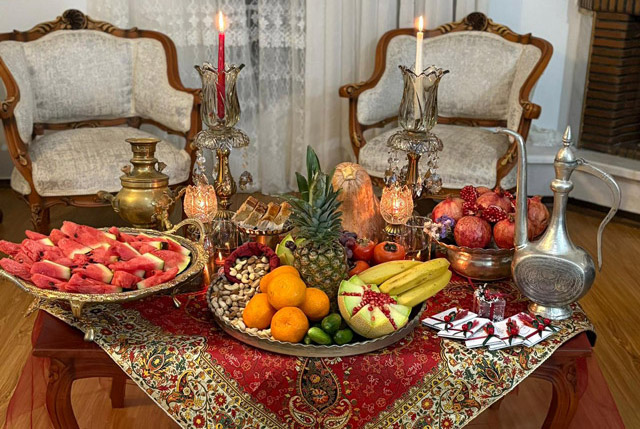 سفره شب یلدا با سماور، شمع و میوه‌های سنتی در خانه‌ای ایرانی